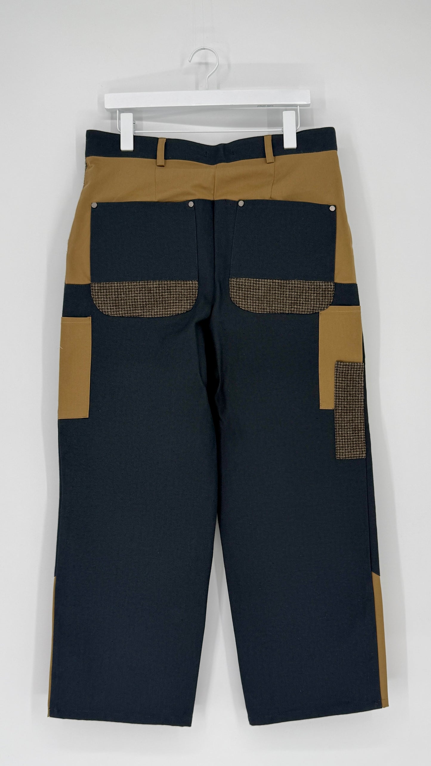 Black and beige pants with textured pockets on a white background