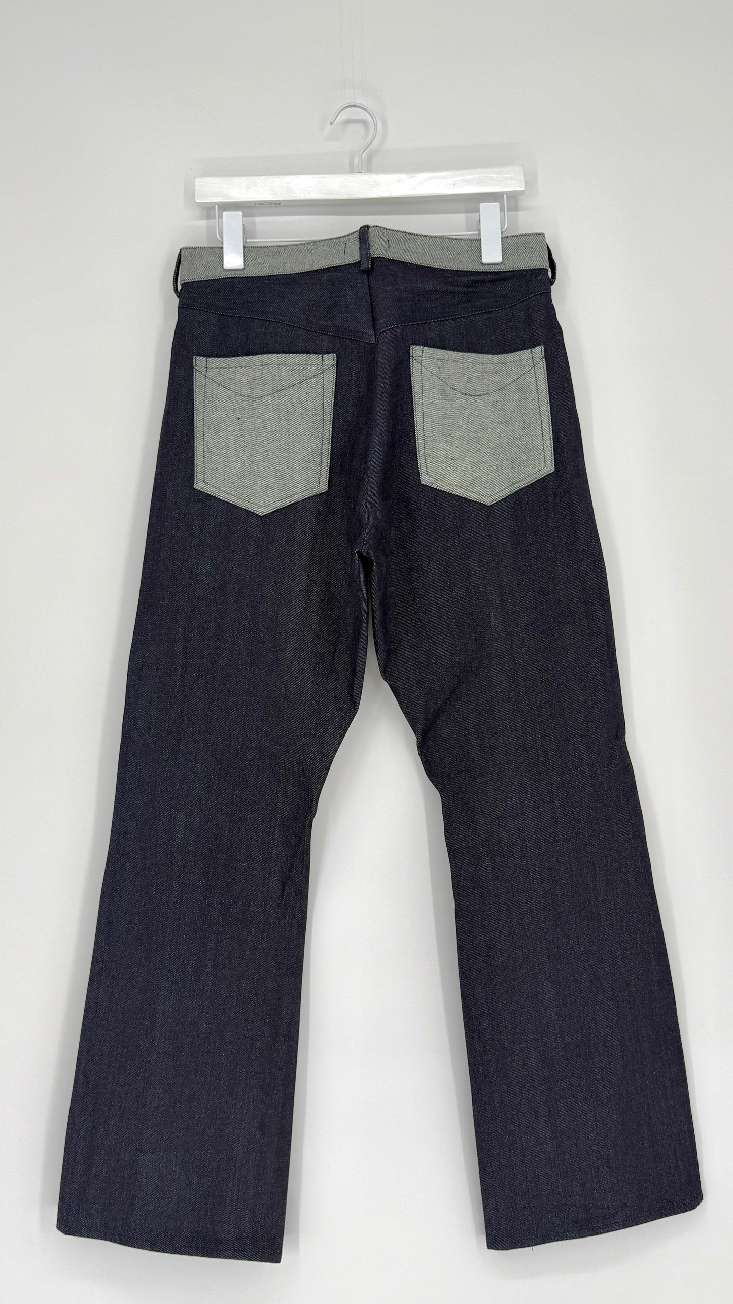 Dark denim jeans with gray patches on a white background