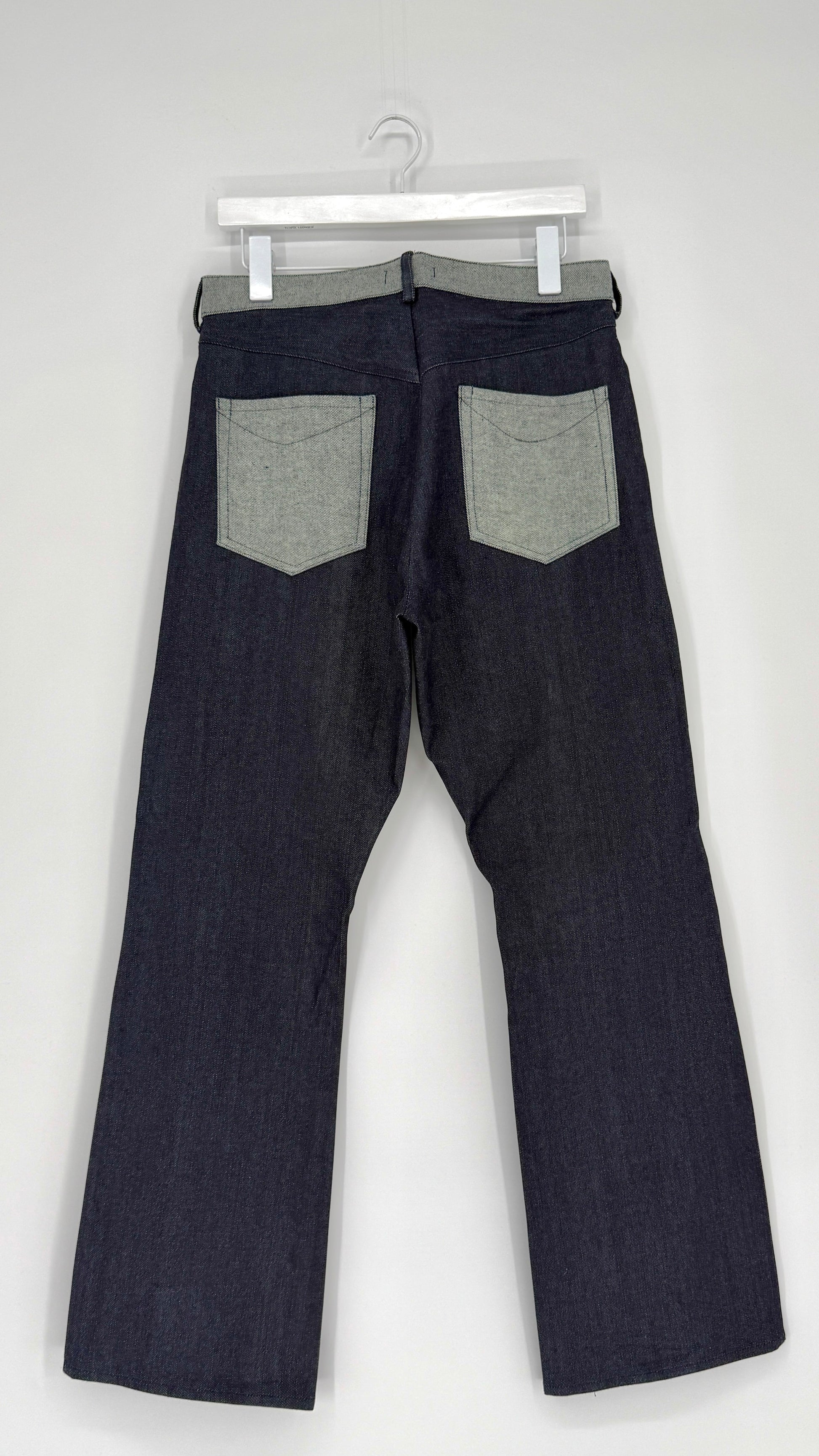 Dark denim jeans with gray patches on a white background