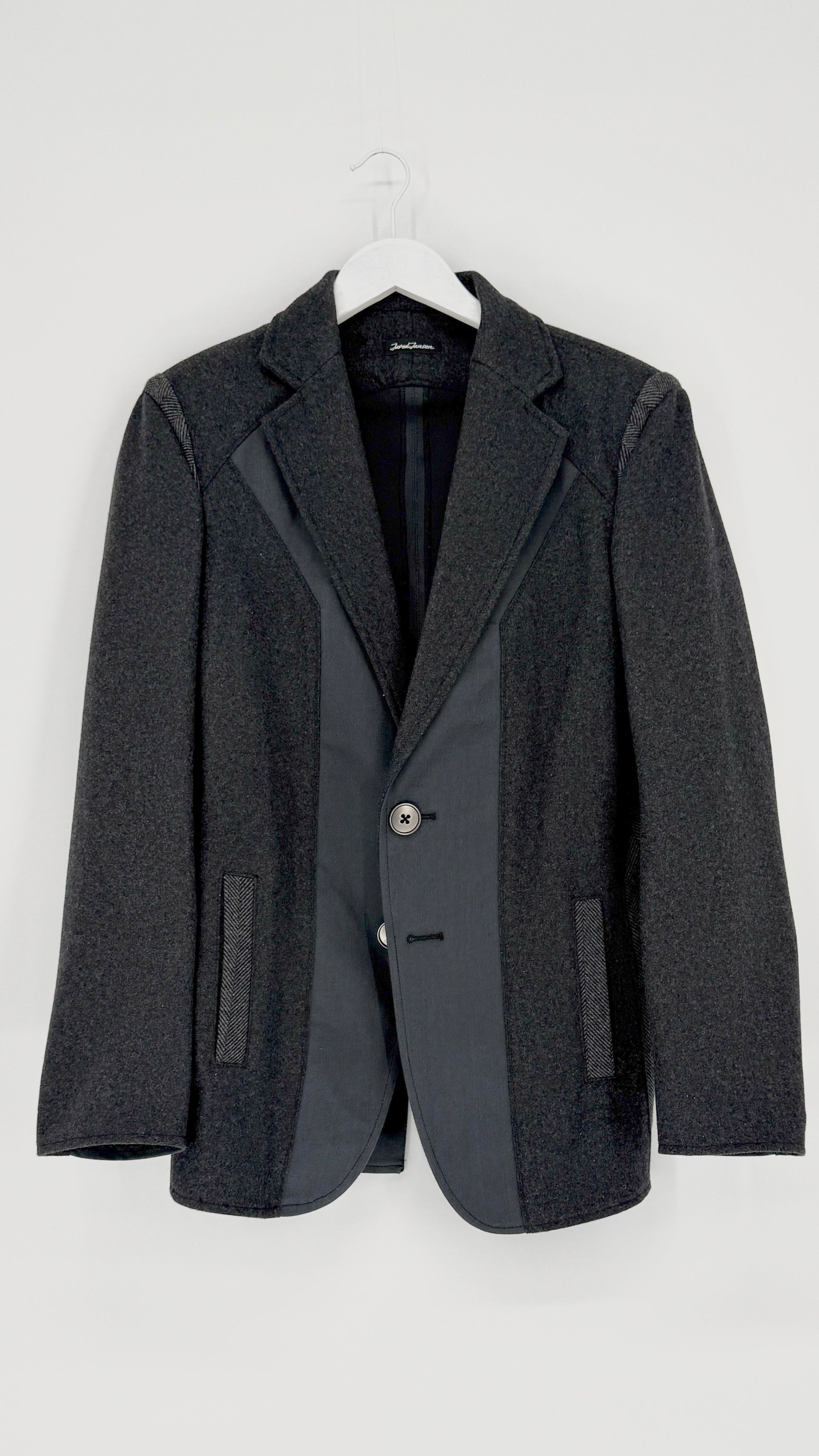 Gray blazer on a hanger against a white background