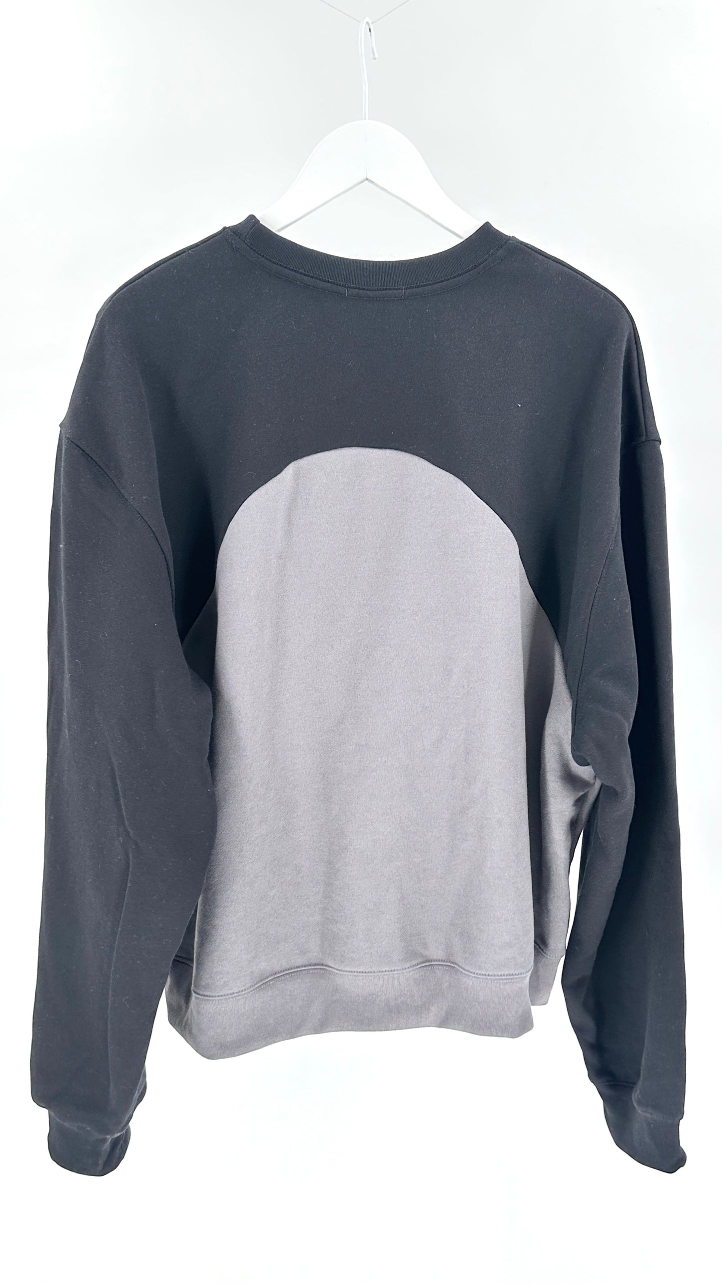 Gray and black sweatshirt on a white hanger against a white background