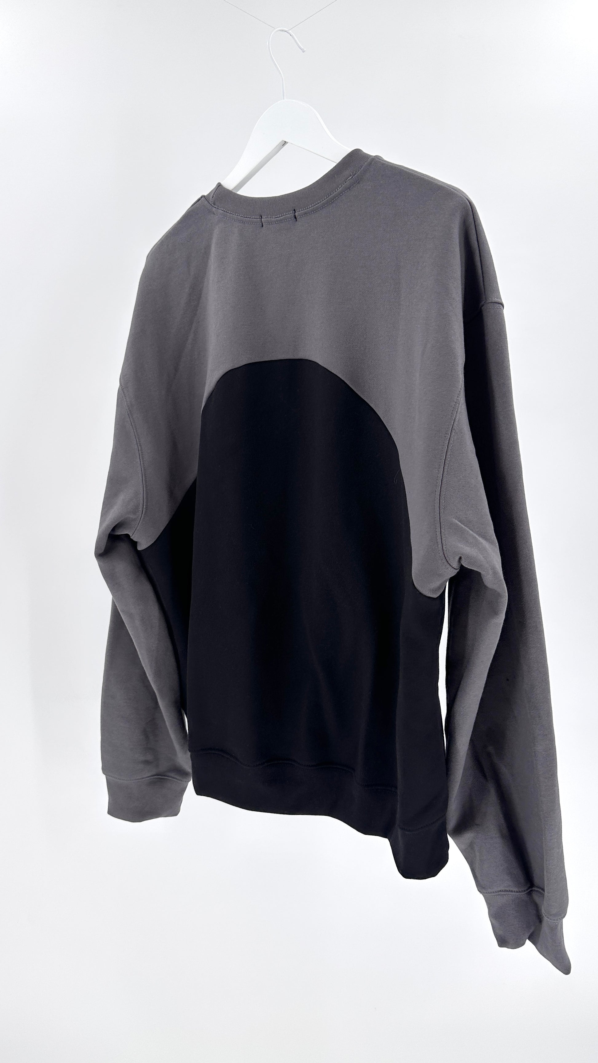 Gray and black sweater on a white hanger against a white background