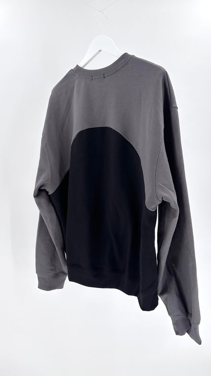 Gray and black sweater on a white hanger against a white background
