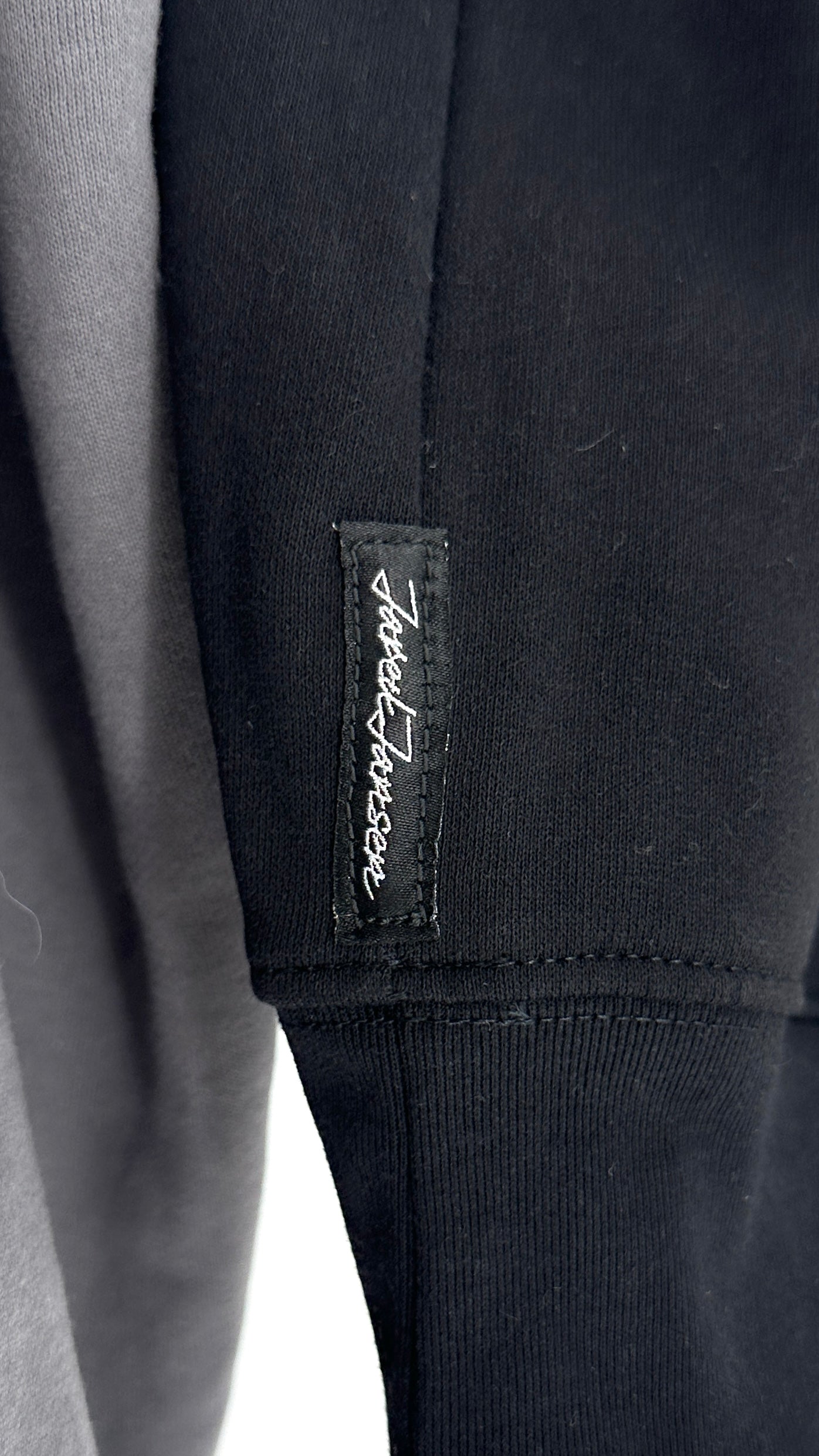 Close-up of a black garment with a brand label on a white background