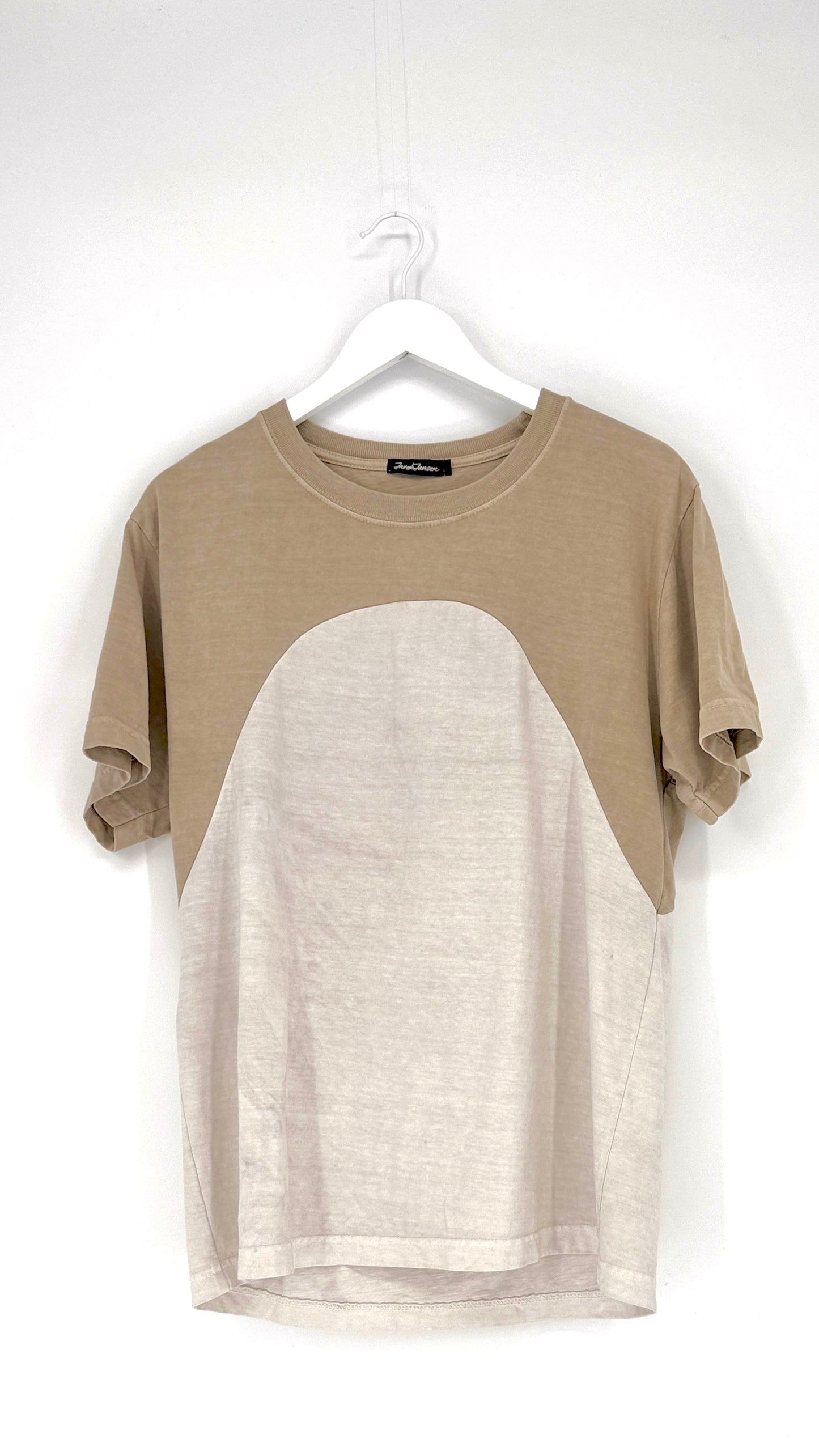 Two-tone t-shirt with beige and white design on a hanger against a white background