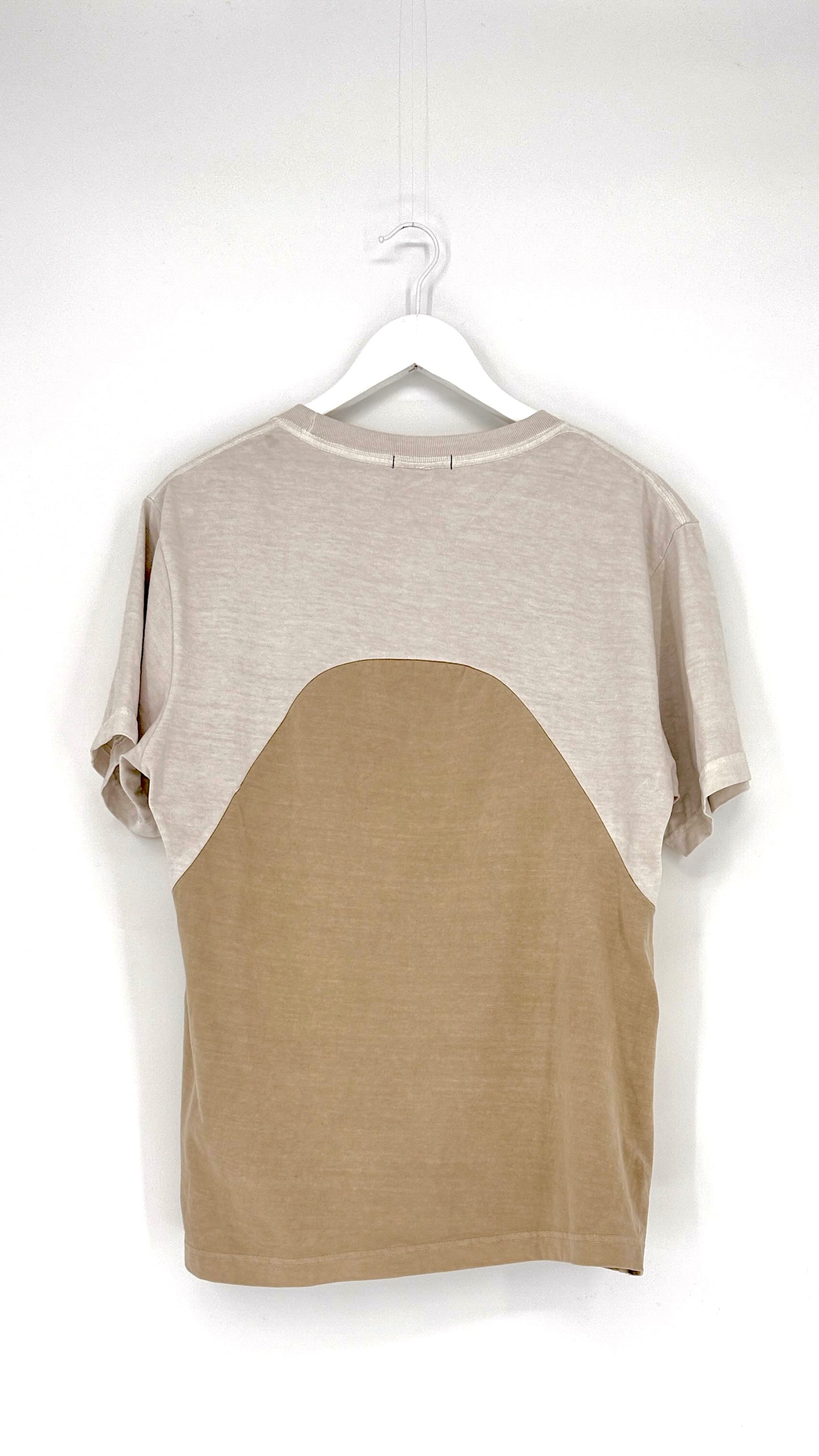 Two-tone shirt with beige and brown sections on a hanger against a white background