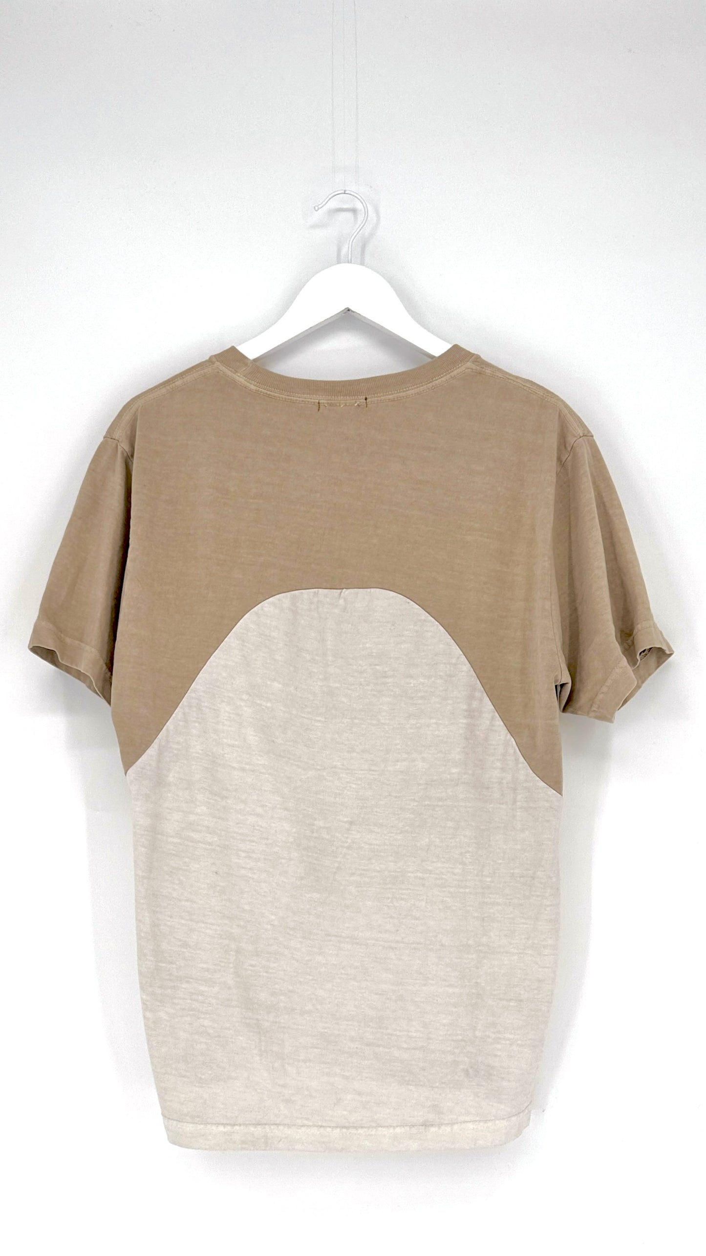 Two-tone t-shirt with beige and white design on a hanger against a white background