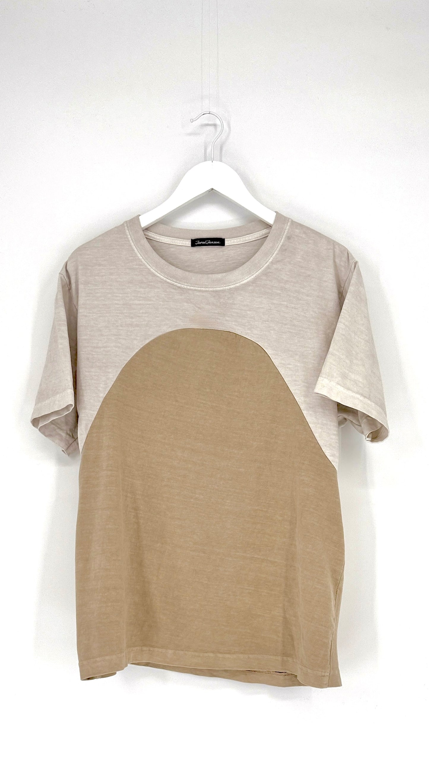 Two-tone t-shirt with gray sleeves and beige body on a hanger against a white background