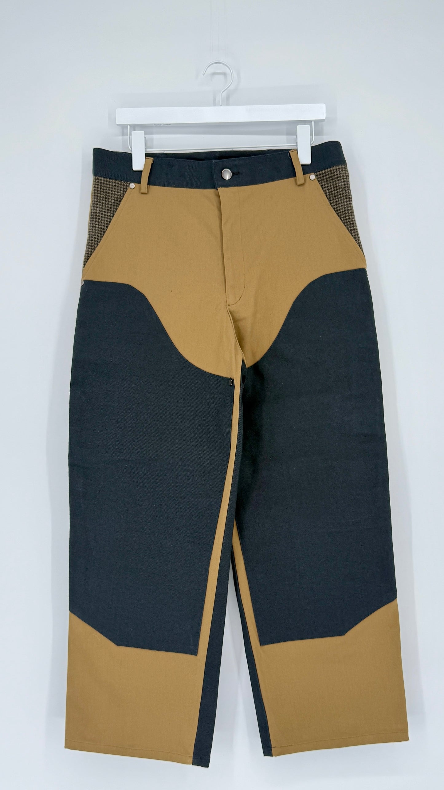 Black and beige pants on a white hanger against a white background